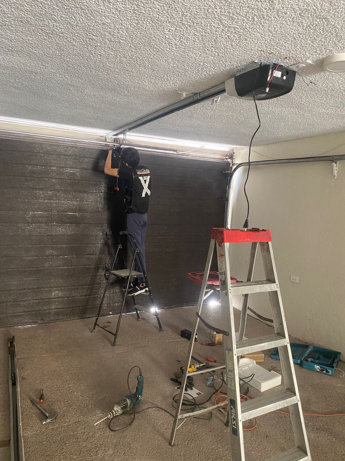 Técnico trabajando en el mecanismo superior de un portón